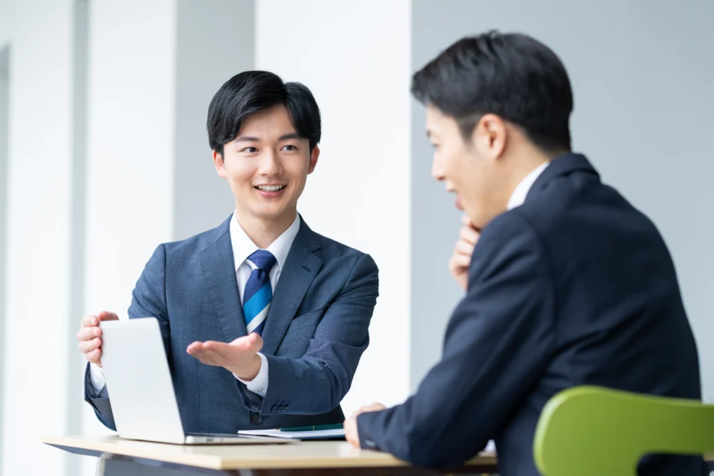 ノートパソコンを使い、Webシステムの構築や連携について話し合うビジネスマン